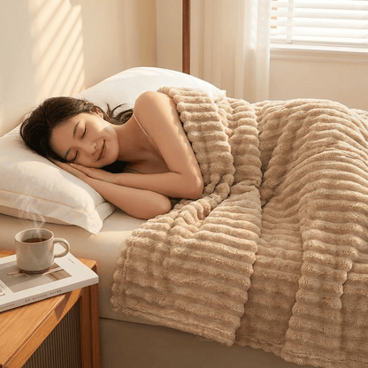 Woman sleeping under a beige blanket with a cup of coffee on a side table.